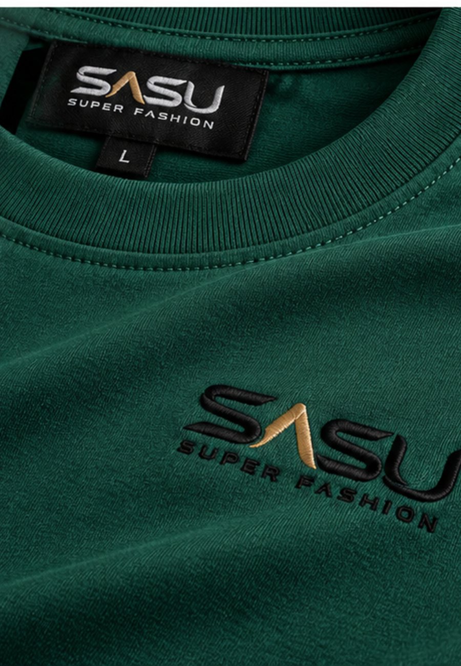 Close-up of the black and gold embroidered logo and ribbed collar on a forest green T-shirt