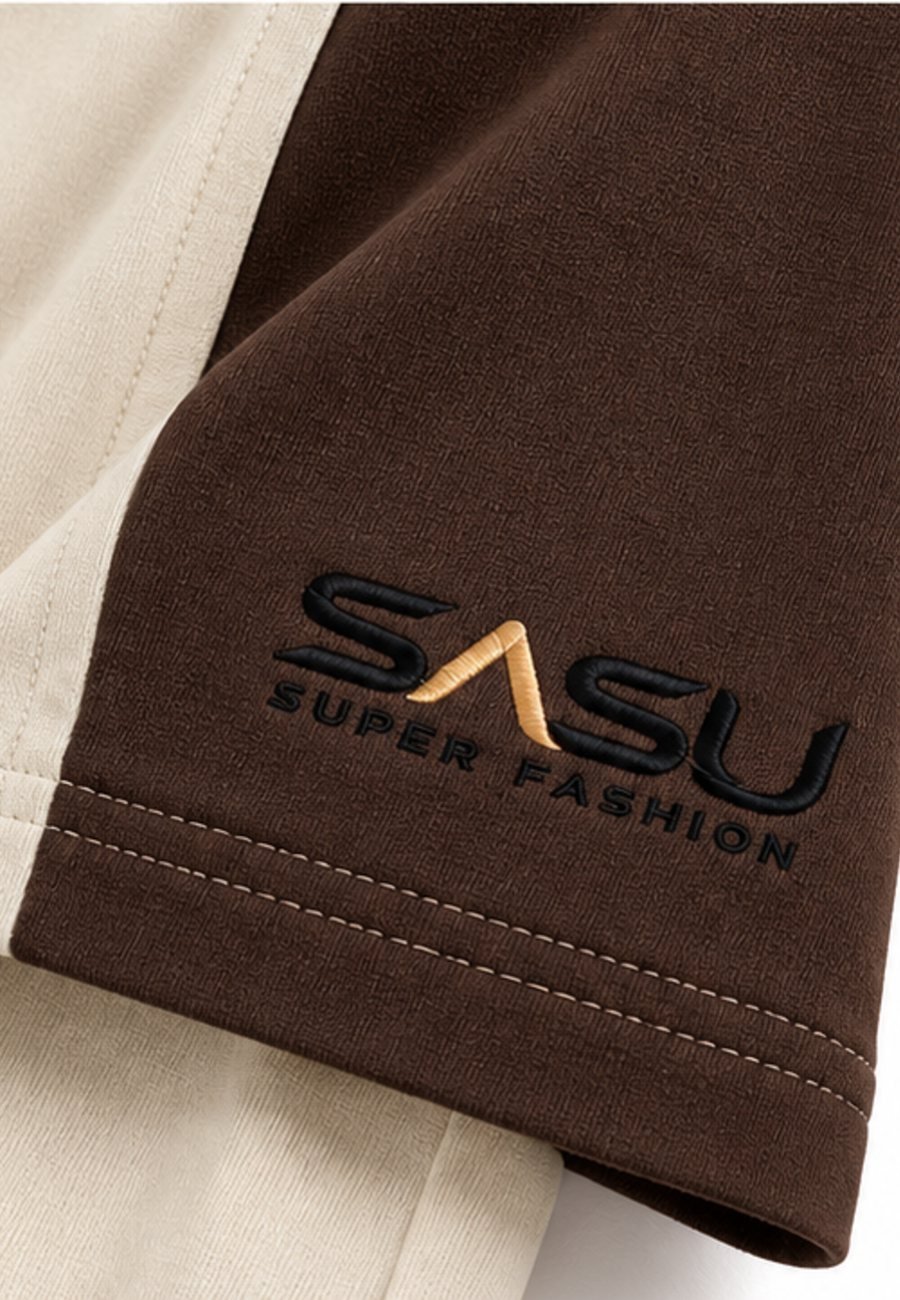 Close-up of the dark brown raglan sleeve with embroidered logo on a cream T-shirt